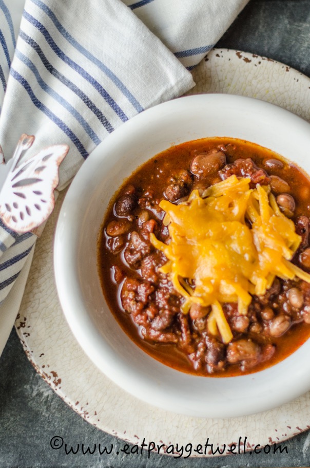 chili with cheese on top in a white bowl