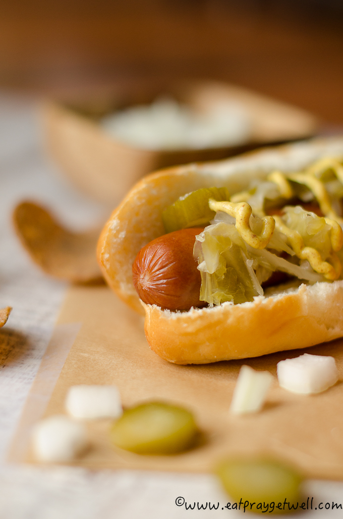 close up of hotdog with a pickle mustard and sauerkraut