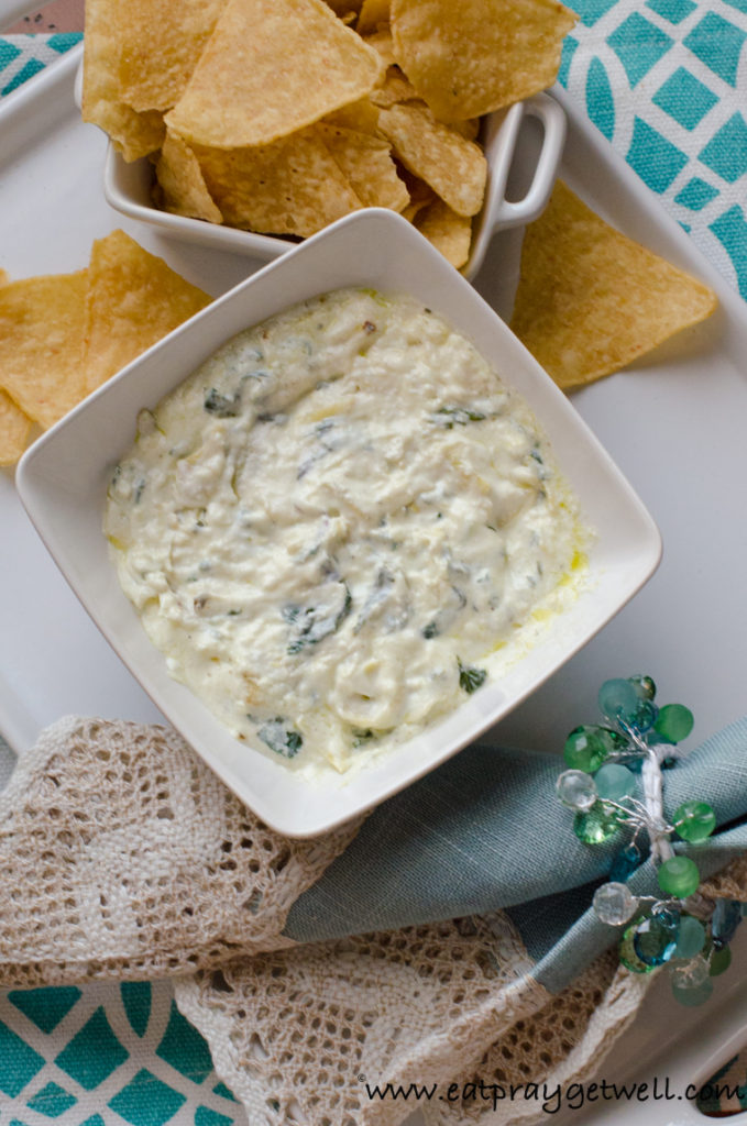 spinach artichoke dip in a white bowl with corn chips 