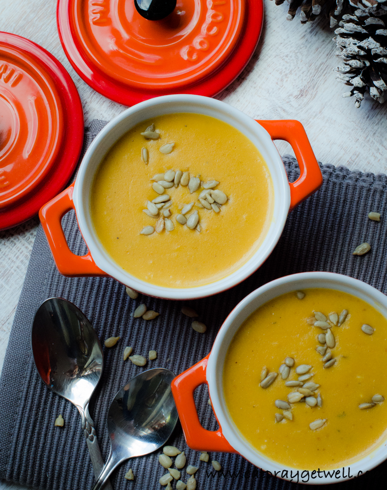 pumpkin soup in orange bowls with sunflower seeds on top