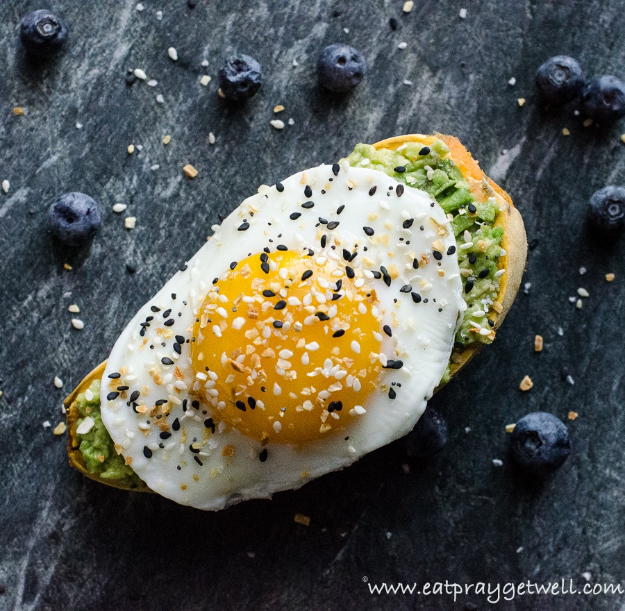 close up of a sweet potato with an egg on top and blueberries around it