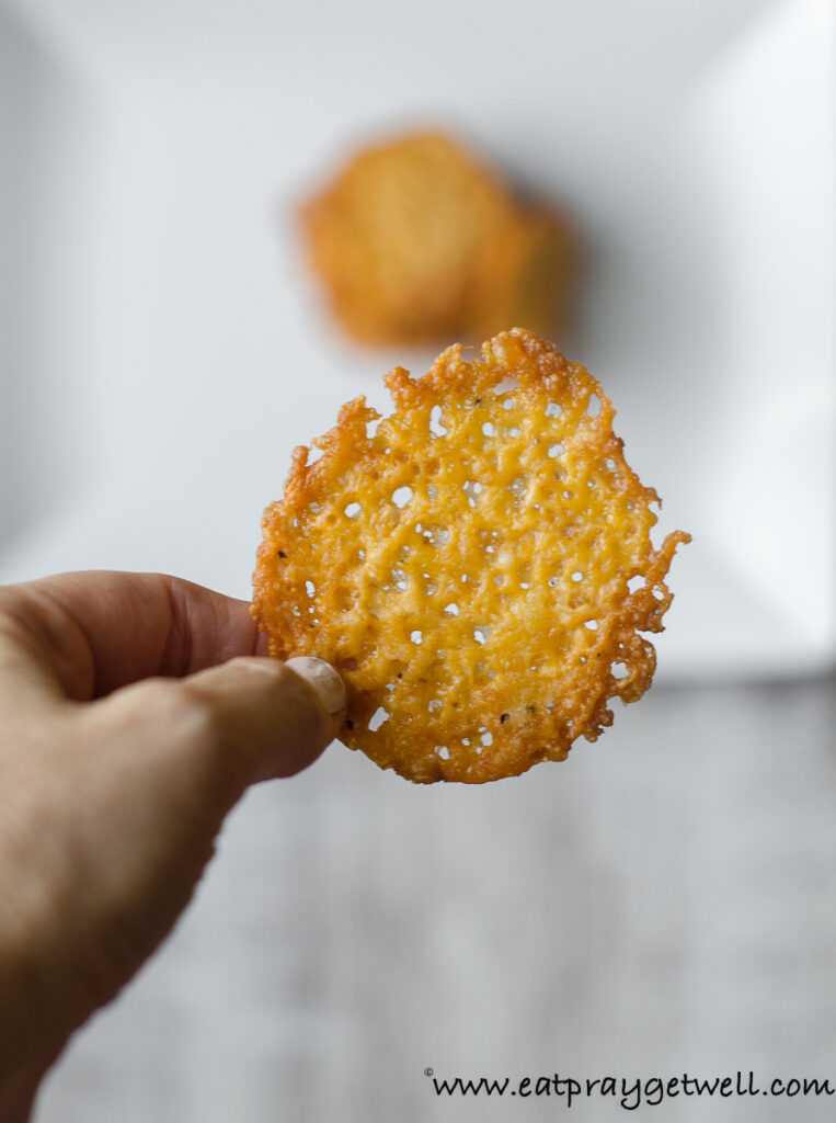 close up of a hand holding up a cheddar parm cracker
